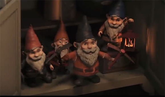 Four animated garden gnomes with pointy hats and white beards standing on a dark wooden shelf.
