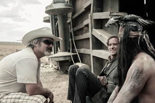 A man in a cowboy hat and sunglasses talks to a man in a suit and a man with long hair and face paint.