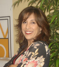 A smiling woman with shoulder-length brown hair wearing a floral patterned top.