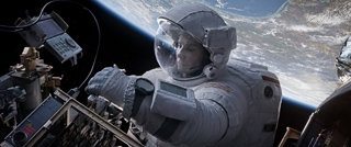 An astronaut in a white spacesuit works near mechanical equipment with Earth in the background.