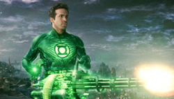 A man in a glowing green superhero suit holds a large, bright green energy weapon against a dark sky.