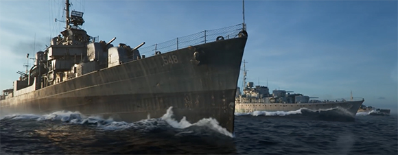 Two large grey naval warships cutting through choppy blue ocean water under a clear sky.