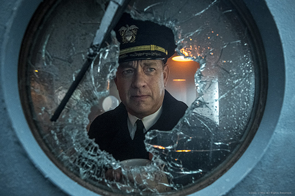 A man in a dark naval officer uniform looks through a shattered circular porthole.