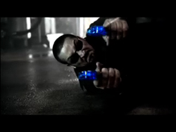 A man in sunglasses holds a blue pill in each hand toward the camera.