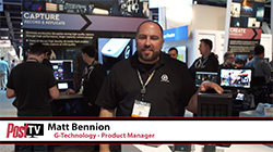 Matt Bennion stands in a trade show booth with technology displays and people in the background.