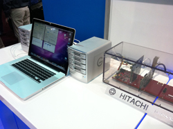 A laptop, a silver computer tower, and internal hardware components inside a clear case on a white table.