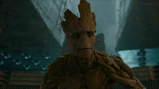 A tree-like humanoid character with textured bark skin stands against a dark, industrial background.
