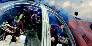 Characters in red and blue outfits sit inside a large, glass-domed spacecraft cockpit.