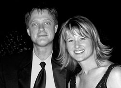 Black and white portrait of a man in a suit and a woman smiling.