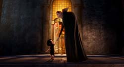 A tall woman in a long black cloak leans down to hold the hand of a small child in a dark stone hall.