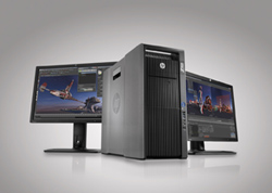 A dark gray computer tower is positioned between two flat-screen monitors. Both monitors display complex graphical interfaces