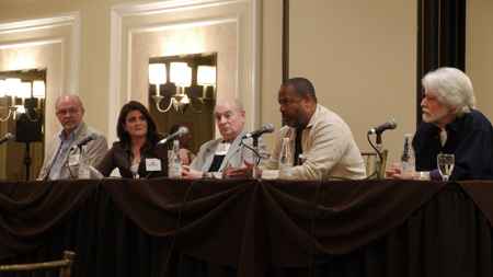 Five people sit behind a long table with microphones during a panel discussion.