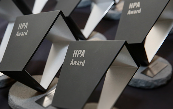 Multiple black and silver HPA Award trophies arranged on stone bases.