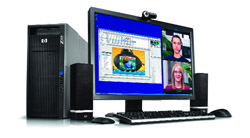 Desktop computer with monitor showing a video call and spreadsheet, tower, keyboard, mouse, and speakers.