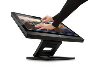 A person's hands touching a large, tilted touchscreen monitor mounted on a black stand.