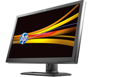An HP computer monitor with a black frame displaying a yellow and orange abstract wave pattern.