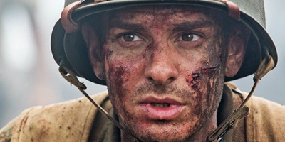 Close-up of a soldier's face covered in dirt and grime, wearing a military helmet.