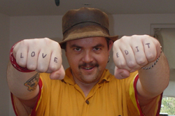 A man wearing a brown hat holds up his fists; 'LOVE' is on his right knuckles and 'EDIT' is on his left.