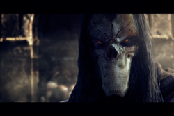 A close-up of a character with a pale, skull-like face and glowing orange eyes.
