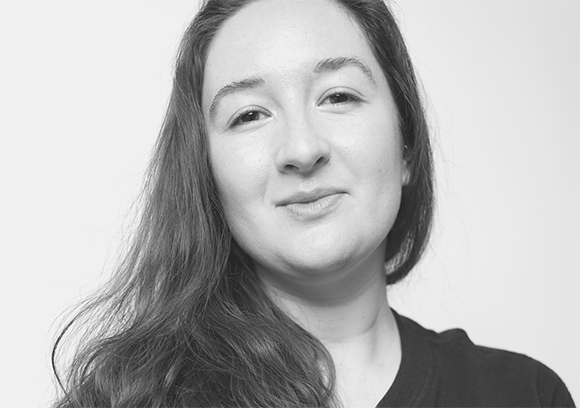 Black and white portrait of a young woman with long hair looking toward the camera.