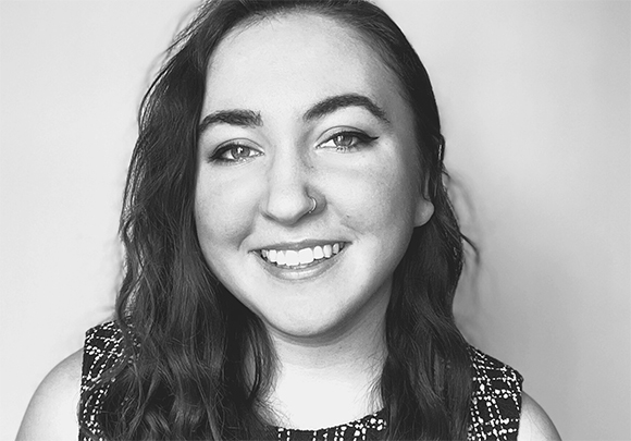 Black and white close-up portrait of a smiling woman with wavy hair and a nose ring.