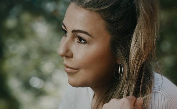 Profile of a woman with light brown hair and hoop earrings looking into the distance.