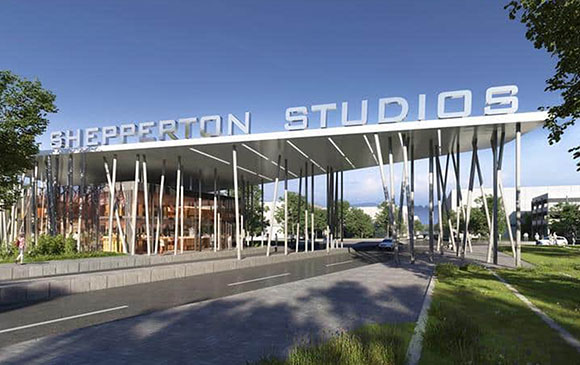 A large white sign reading 'SHEPPERTON STUDIOS' mounted on a modern building with tall support pillars.