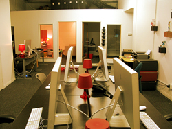 A row of computer monitors and keyboards on a long desk in a modern office setting.