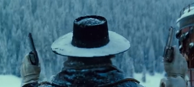 Rear view of a person in a wide-brimmed hat holding two handguns in a snowy forest.
