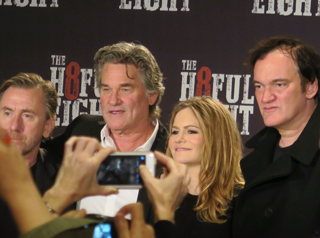 Four people pose for a photo in front of a dark background with white and red text.