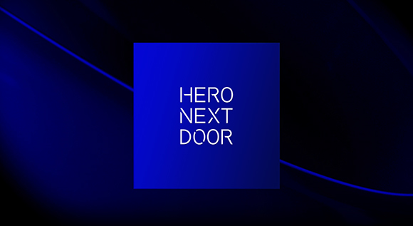 A blue square containing the white text 'HERO NEXT DOOR' against a dark blue wavy background.