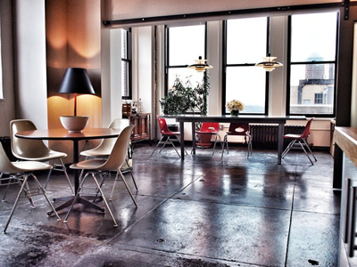 A bright room with large windows, a round table with chairs, and a long conference table.