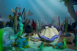 Stylized underwater scene with large clams having eyes and colorful coral under light rays.