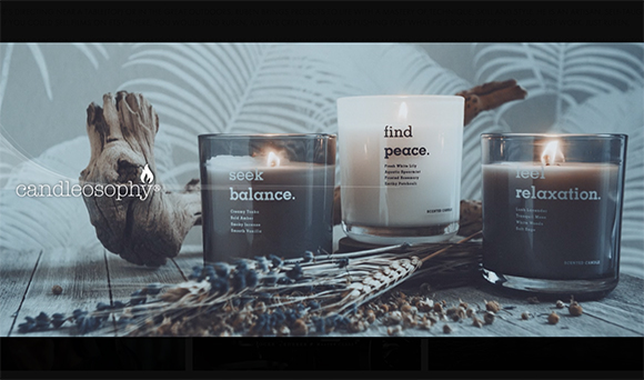 Three glass candles labeled 'seek balance', 'find peace', and 'feel relaxation' arranged with driftwood and lavender.