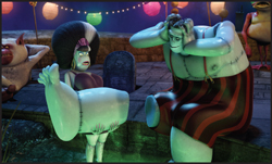Animated monsters sit around a gravestone under colorful lanterns at night.