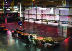 An empty production studio with overhead lighting trusses and a long control desk in the foreground.