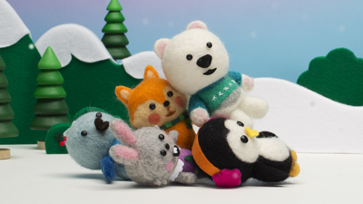 Group of small felted animal toys including a polar bear, fox, penguin, rabbit, and koala in a snowy scene.
