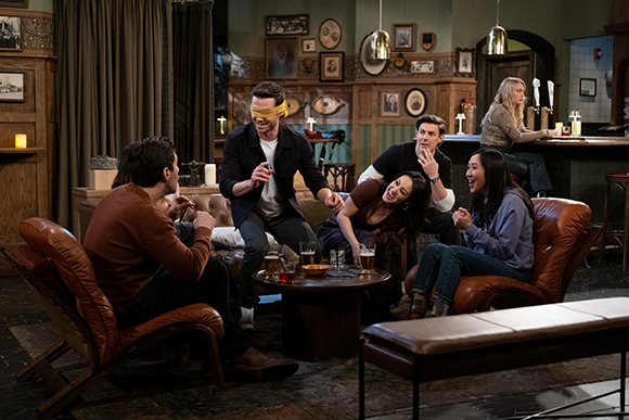 A group of people laughing and playing a game around a low table in a decorated lounge.