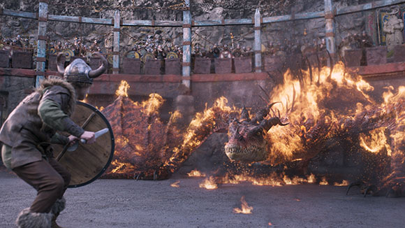 A Viking warrior with a shield and sword faces a massive, fire-covered dragon in a stone arena.