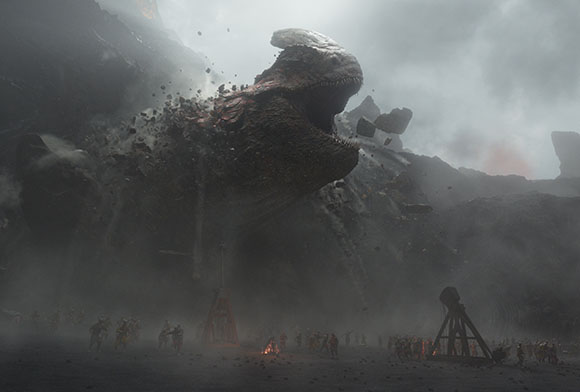 A giant, dark, textured creature with a large head and open mouth towers over small figures in a misty canyon.