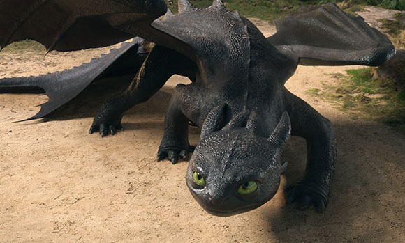 A black, scaly dragon with large wings lies low to the sandy ground, looking forward with green eyes.