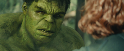 A close-up of a large, muscular green-skinned character with a furrowed brow looking at a person with red hair.