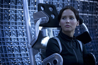 A woman with dark hair sits in a futuristic silver metallic chair against a grid background.