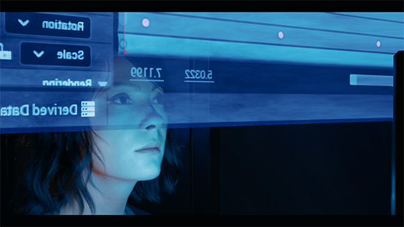 A person's face viewed through a blue-tinted digital interface with various data sliders and menus.