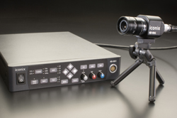 A black Iconix control box sits next to a small camera mounted on a miniature tripod against a dark background.