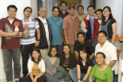 A large group of diverse people smiling and posing for a group photo in an indoor setting.