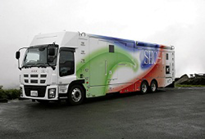 A white heavy-duty truck featuring green, blue, and red swooping graphics on its side.