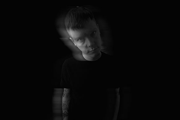 Black and white portrait of a man with a motion blur effect against a dark background.