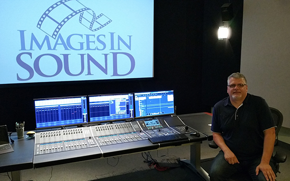 A man sits beside a large audio mixing console in a studio with a screen displaying 'Images in Sound'.