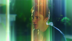 A man looks to the side through vertical streaks of green and orange light.